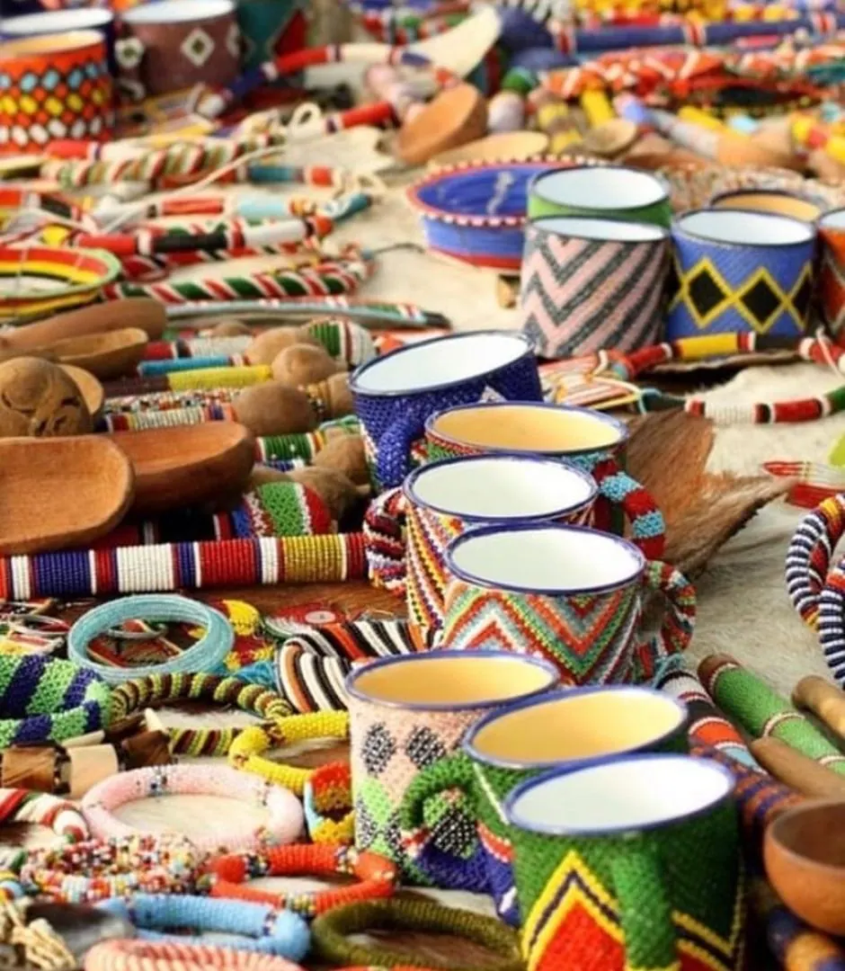 Beaded bangles, wooden spoons and enamel mugs wrapped in beadwork laid out on a hide